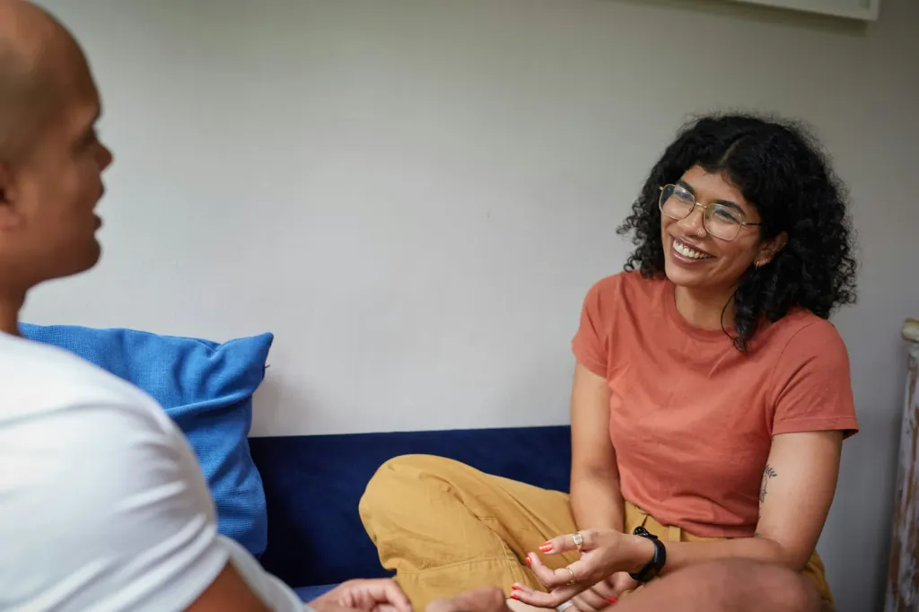 A student smiling while talking with a peer on a couch